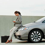 Businesswoman texting on mobile phone in car park