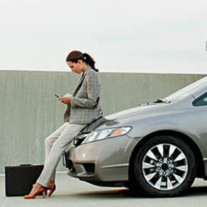 Businesswoman texting on mobile phone in car park