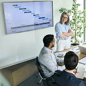 Senior female ceo and multicultural business people discussing company presentation at boardroom table. Diverse corporate team working together in modern meeting room office. Top view through glass