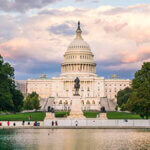 The United States Capitol building at sunset wirh reflection in water.