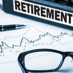 "Retirement" written on spine of a binder sitting on top of documents with a pair of glasses