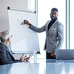 A young manager presenting the graph results on the whiteboard to the board at the conference room.