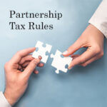 Two hands holding a puzzle piece that appear to fit together and the words "Partnership Tax Rules" above them