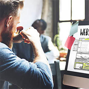 Man sipping coffee and working on a website on his computer