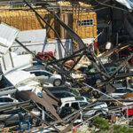 destroyed industrial building with damaged cars under it