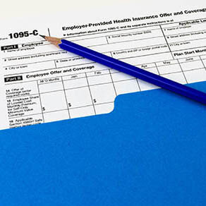 Tax Form 1095-C in a folder with a pencil