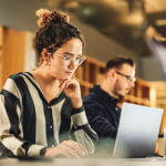 Woman working on her laptop, man next to her working on a laptop as well