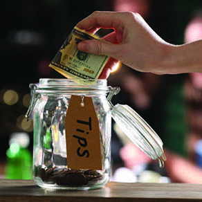 person placing tips into a tip jar