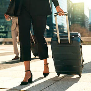 Professional woman walking and pulling a suitcase
