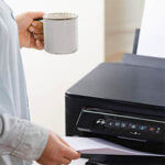 Office job. Secretary or office manager woman using printer, scanner or laser copy machine.