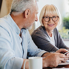 Senior couple doing home finances using laptop indoors