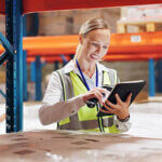 Woman using a tablet and scanner for boxes in warehouse