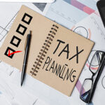 op view of office desktop with paperwork, glasses and other items. Tax planning concept