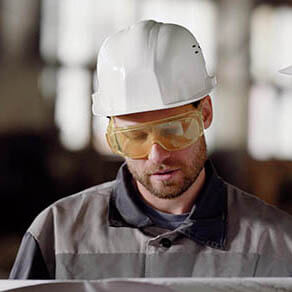 Adult superintendent and architect in protective helmets on the head call a smart phone to the customer of the project, in order to approve changes in the existing plan of building modernization