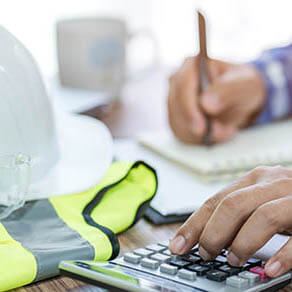 Engineer typing on calculator at a desk
