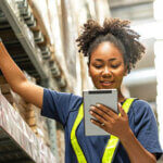 Woman working with a tablet walks through the warehouse to check inventories