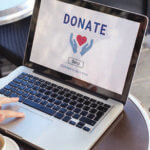 Open laptop with the words "Donate" and open hands and a heart icon