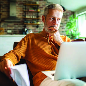 Man in a home office working with a laptop on his lap