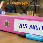 Financial concept about IRS AUDIT Internal Revenue Service with inscription on the Box File. Businessman working with documents sending email, mobile phone