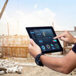 Hands using digital tablet with Construction Management Software on blurred construction site as background