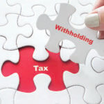 White puzzle with missing piece in red reading "tax" and final "witholding" piece being placed