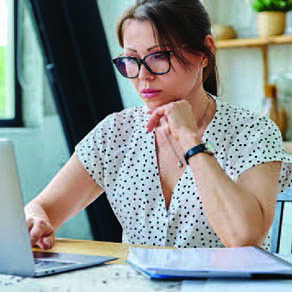Woman with hand resting on her chin looking closely at her laptop