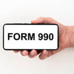 form 990 inscription on the screen of a phone being held