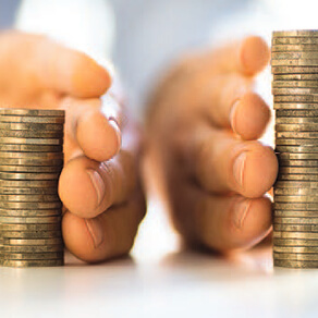 Two hands with each guarding a stack of coins