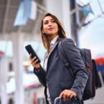 Business woman looking up from her phone as she walks through airport