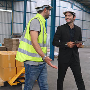 Factory workers deliver boxes package on a pushing trolley in the warehouse . Industry supply chain management concept .