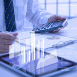 Businessman or analyst holding calculator while reviewing financial statements for business performance or cash flow analysis