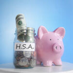 Jar with cash and coins with "H.S.A." on it next to piggy bank
