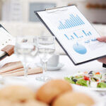Close-up of open notepad and business document in male hand during business lunch
