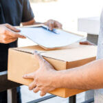 Someone dropping off a box and papers to another person