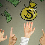 Yellow money bag and dollar bills hanging from above with hands grabbing for them