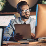 Man sitting in front of a computer screen in a dimly lit room