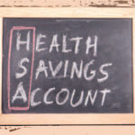 The words “health savings account" spelled out in chalk on a board with the “H,S, A” circled together in red.