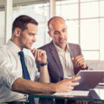 Two businessmen in discussion using computer laptop