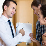 Man holding up and looking over a contract with a husband and wife