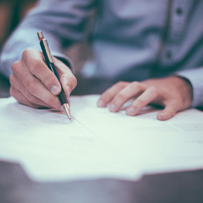 Man writing with pen on shadowed out paper