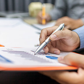 Person pointing at chart on paper with pen