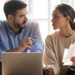 A husband and wife sitting in front of a laptop in a discussion