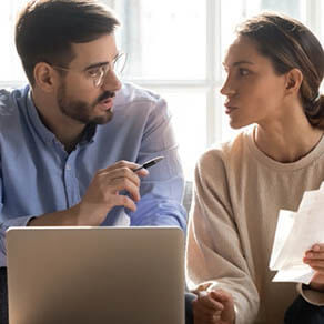 A husband and wife sitting in front of a laptop in a discussion