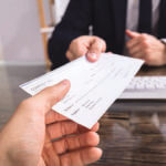 A person is receiving a check from another person.