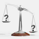 Silver balancing scall with brown bottom and a question mark on the raised end and question mark on the lower