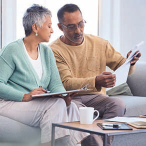 Older couple sitting on a couch looking at documents