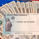 Stack of twenty dollar bills fanned out with a check from the US treasury payable to every US citizen