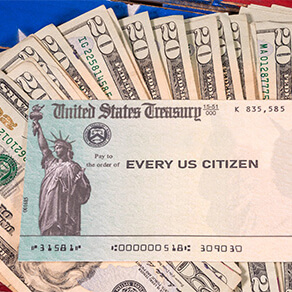 Stack of twenty dollar bills fanned out with a check from the US treasury payable to every US citizen