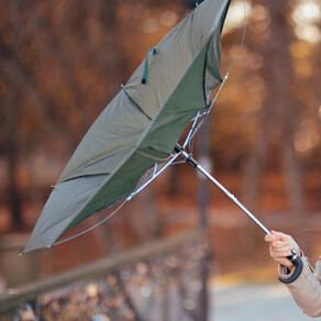 A hand holding an umbrella that is opening inside out