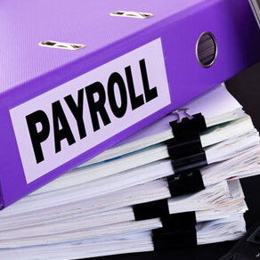 Stacks of papers with purple binder on top with the word payroll on side